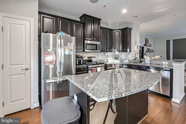 kitchen with dark hardwood / wood-style floors, a kitchen breakfast bar, kitchen peninsula, and stainless steel appliances