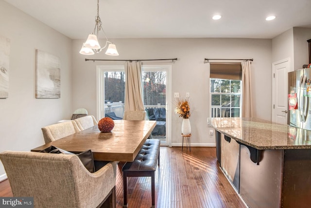 dining space with dark hardwood / wood-style flooring and an inviting chandelier