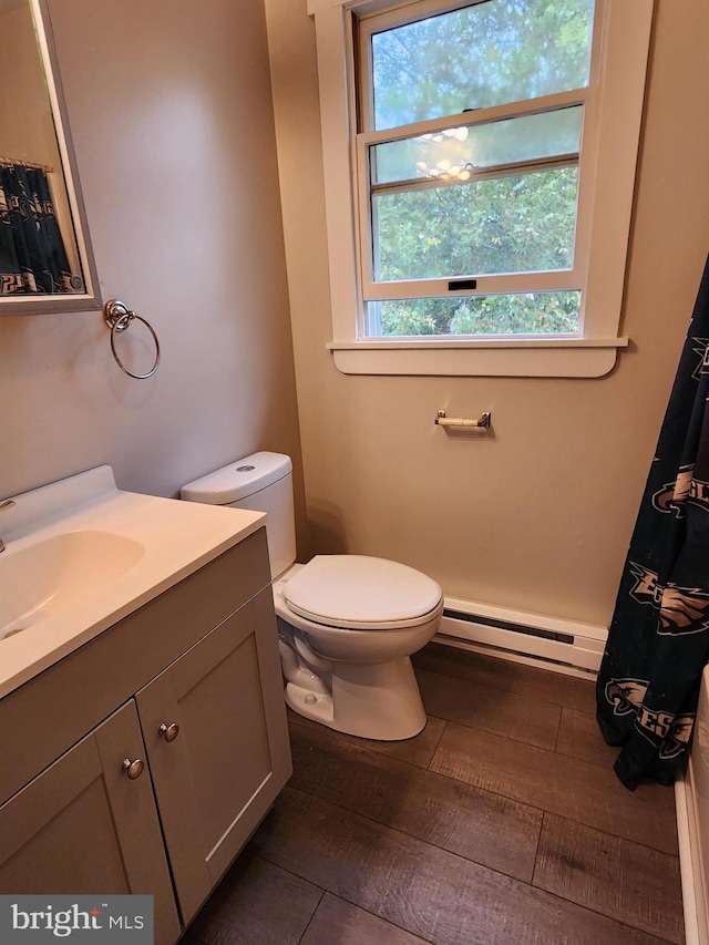 bathroom with hardwood / wood-style flooring, vanity, toilet, and a baseboard radiator