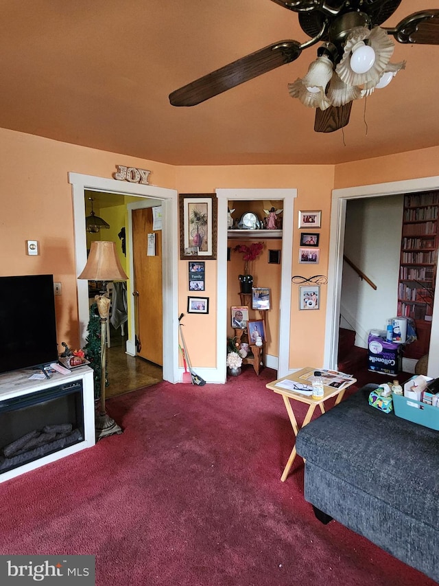 living room featuring ceiling fan and dark carpet