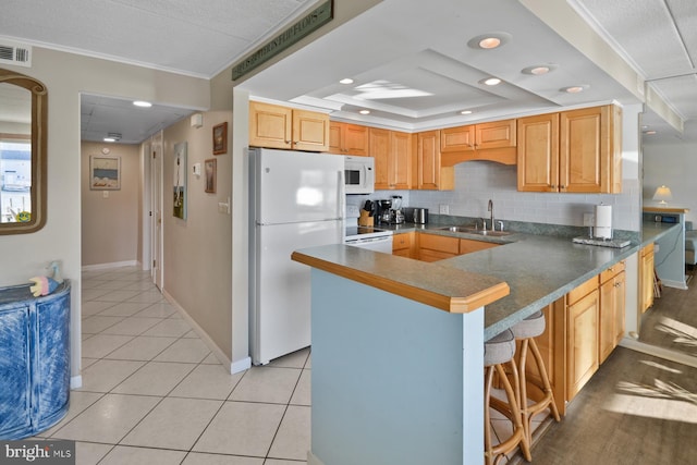 kitchen with a breakfast bar, white appliances, sink, crown molding, and kitchen peninsula