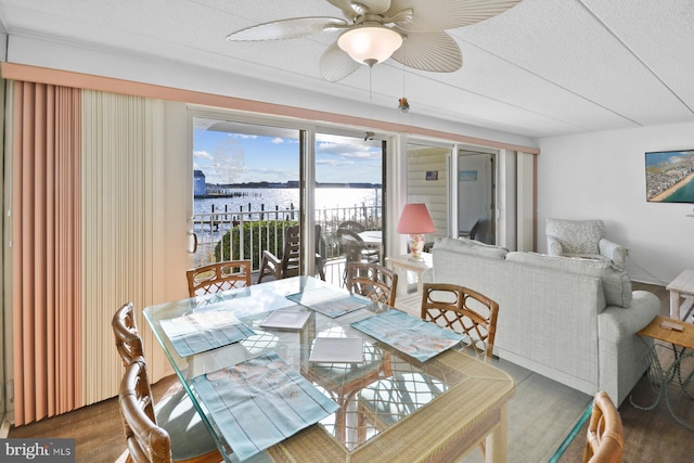 dining room with ceiling fan, hardwood / wood-style floors, a water view, and a textured ceiling