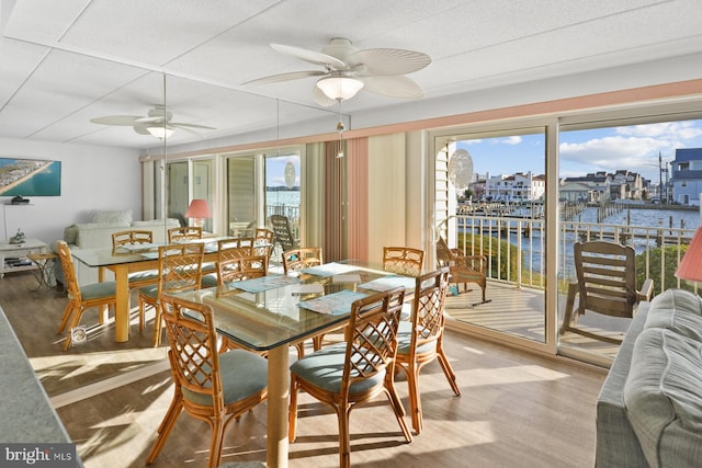 dining area featuring a water view, hardwood / wood-style flooring, and ceiling fan