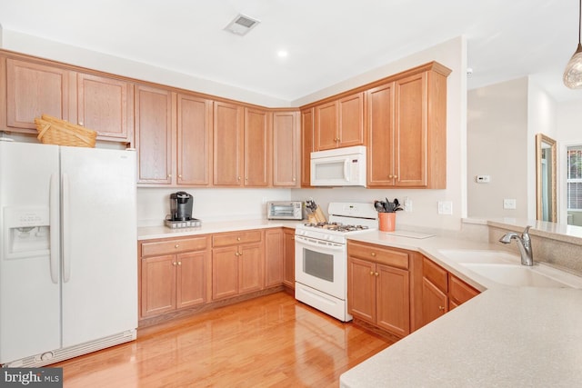 kitchen featuring pendant lighting, white appliances, light hardwood / wood-style floors, and sink