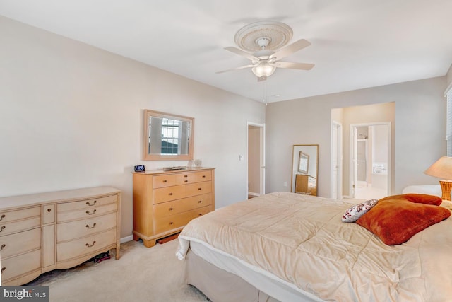 bedroom featuring light carpet, ensuite bathroom, and ceiling fan