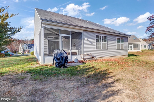 back of property with a sunroom and a yard