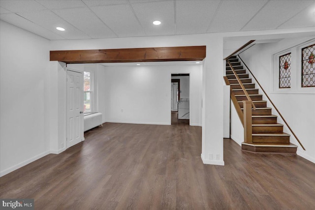 basement featuring radiator, a drop ceiling, and dark hardwood / wood-style floors