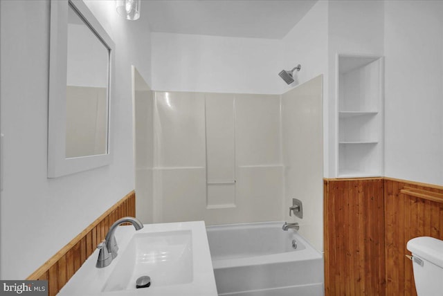 full bathroom featuring toilet, sink, wooden walls, and bathtub / shower combination