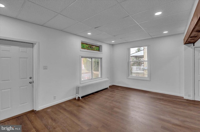 foyer entrance featuring radiator heating unit, a drop ceiling, and dark wood-type flooring