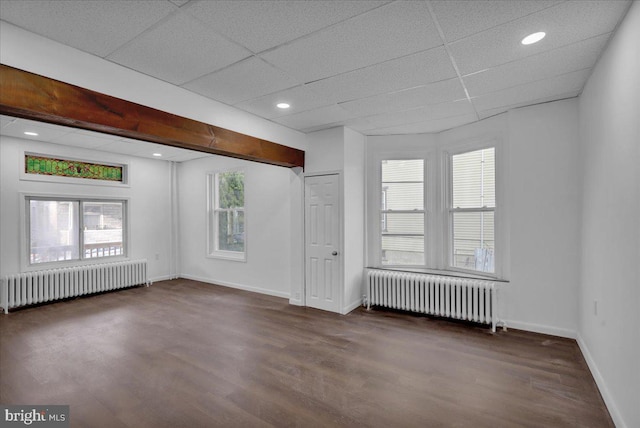 unfurnished room with a drop ceiling, dark hardwood / wood-style flooring, and radiator