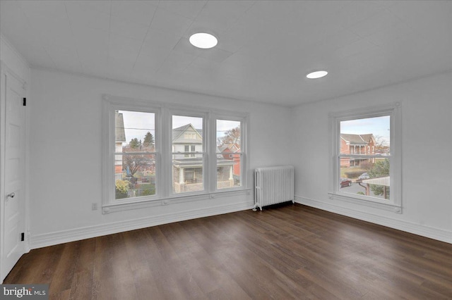 empty room with dark hardwood / wood-style floors and radiator