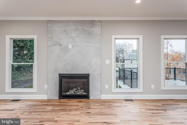 unfurnished living room with crown molding, a large fireplace, and light hardwood / wood-style flooring