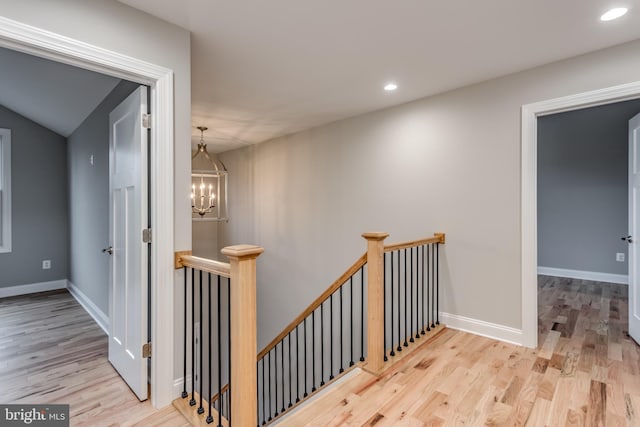 corridor with light hardwood / wood-style floors and an inviting chandelier