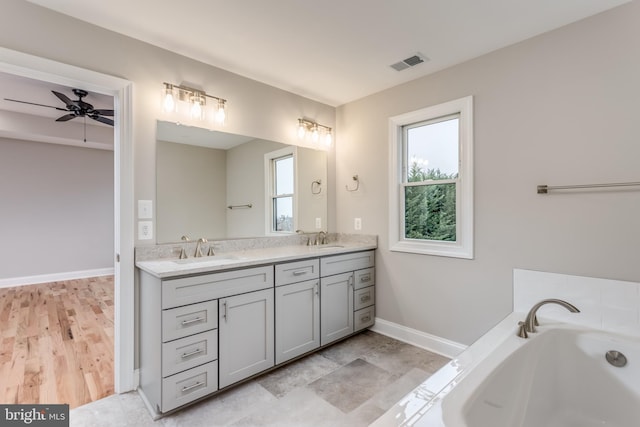 bathroom featuring ceiling fan, a washtub, vanity, and hardwood / wood-style floors