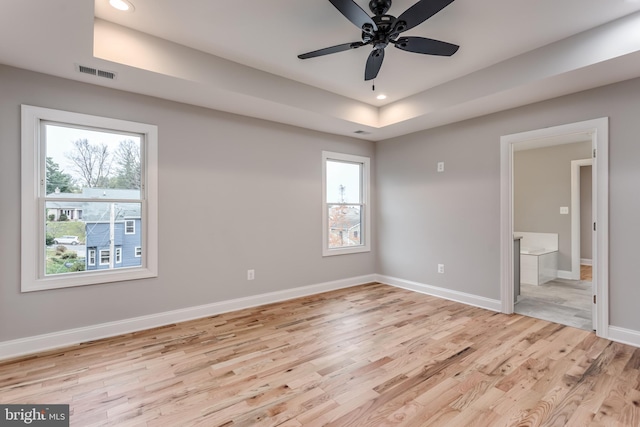 unfurnished bedroom with ceiling fan, light hardwood / wood-style flooring, connected bathroom, and multiple windows