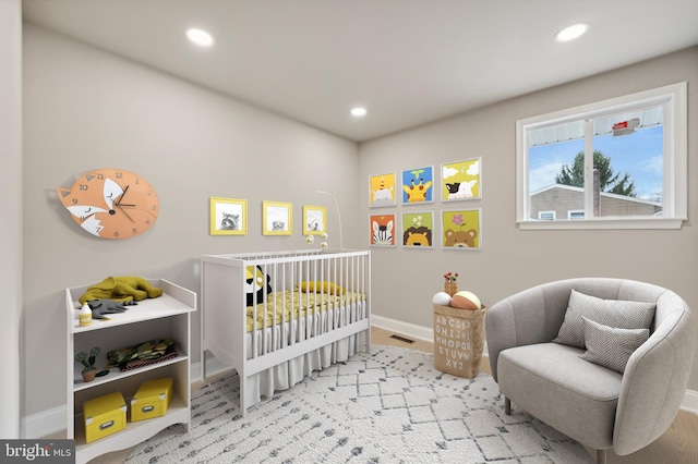 bedroom featuring light hardwood / wood-style floors and a nursery area