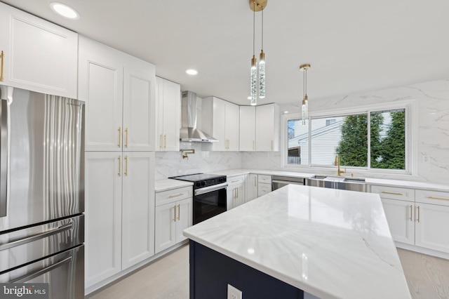 kitchen with white cabinetry, light stone countertops, wall chimney range hood, and appliances with stainless steel finishes