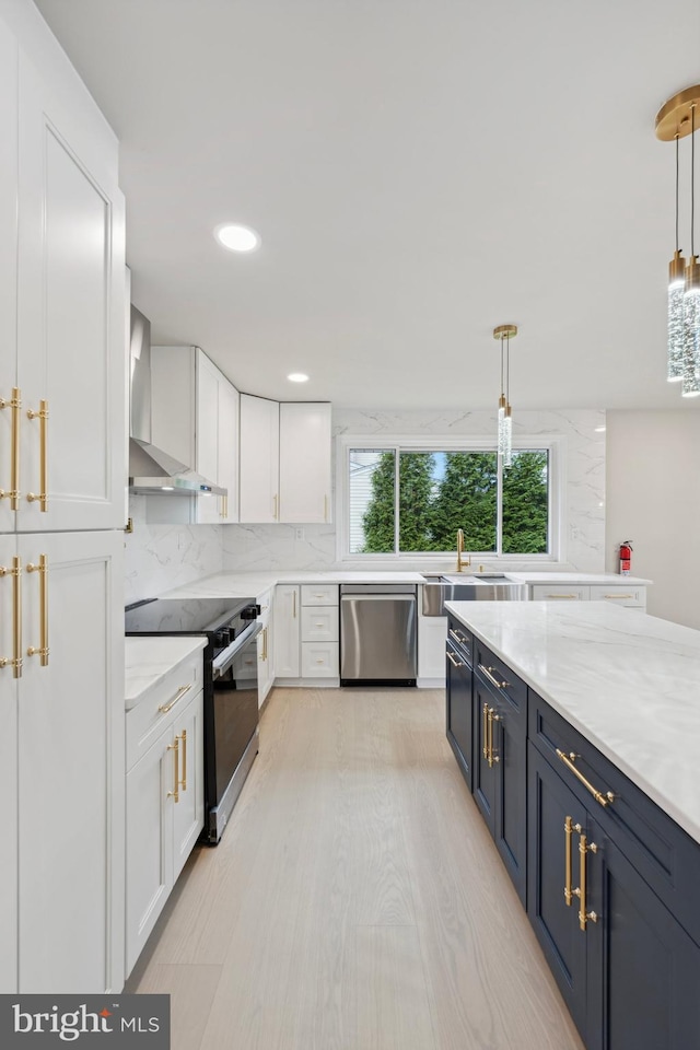 kitchen with white cabinets, hanging light fixtures, wall chimney range hood, and appliances with stainless steel finishes