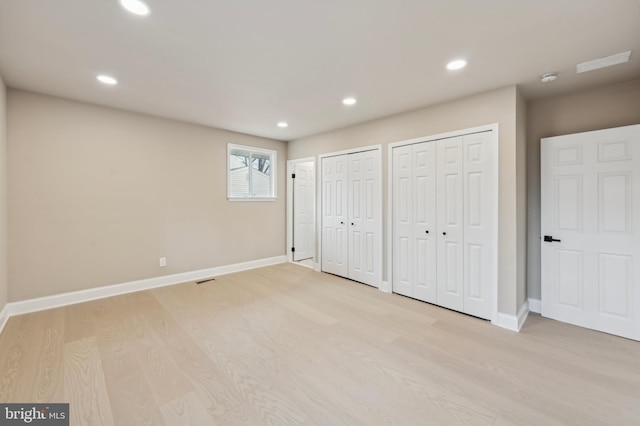 unfurnished bedroom with multiple closets and light hardwood / wood-style flooring