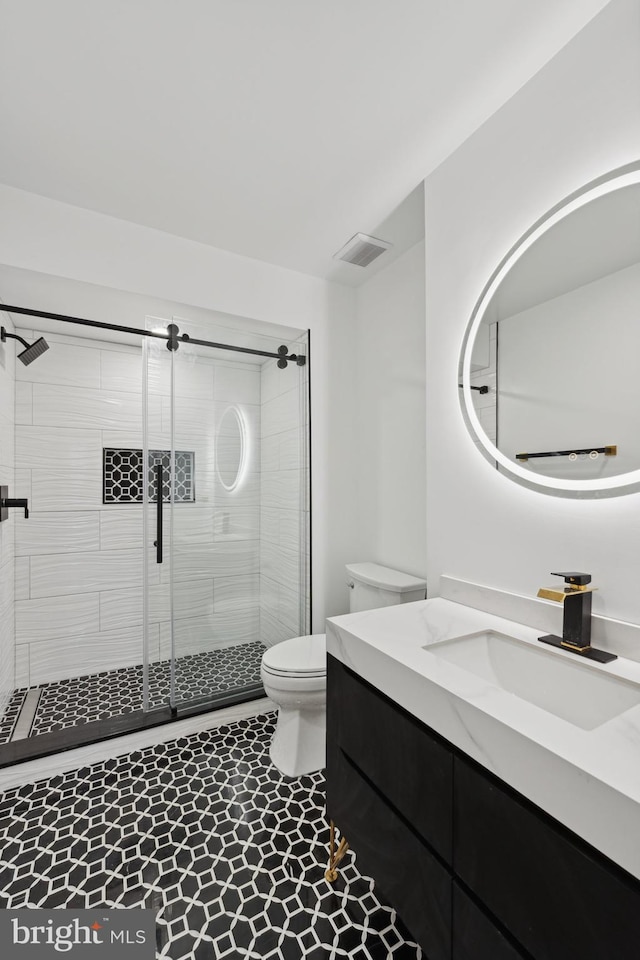 bathroom with tile patterned flooring, vanity, toilet, and walk in shower