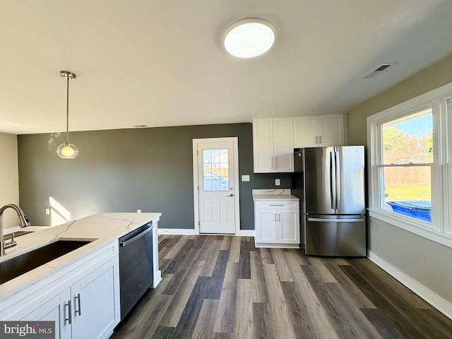 kitchen featuring stainless steel appliances, white cabinetry, hanging light fixtures, and a healthy amount of sunlight