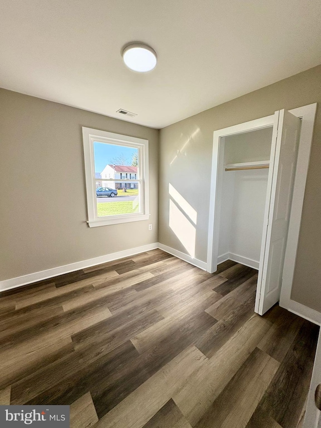 unfurnished bedroom featuring dark hardwood / wood-style floors and a closet