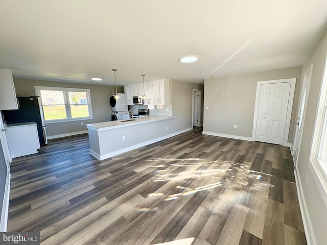 kitchen with hanging light fixtures, dark hardwood / wood-style floors, kitchen peninsula, white fridge, and white cabinets