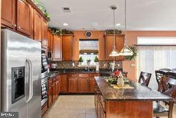 kitchen with a center island, hanging light fixtures, tasteful backsplash, stainless steel fridge, and a breakfast bar area