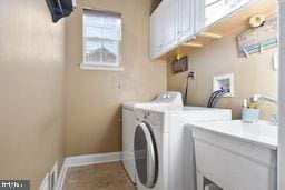 washroom with washer and dryer and cabinets