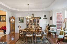 dining space featuring a tray ceiling, dark hardwood / wood-style floors, and an inviting chandelier