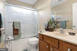 full bathroom with shower / bath combination with glass door, vanity, and toilet