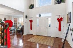 entryway featuring a towering ceiling and dark wood-type flooring