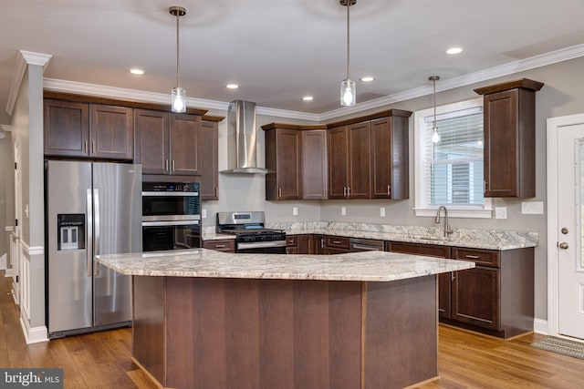 kitchen with hardwood / wood-style floors, hanging light fixtures, stainless steel appliances, and wall chimney range hood