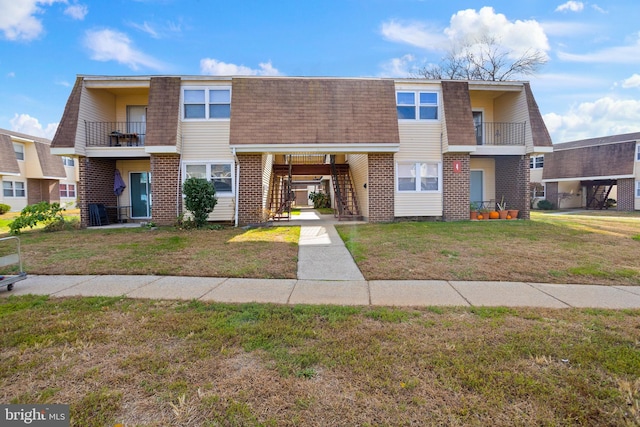 townhome / multi-family property featuring a balcony and a front lawn