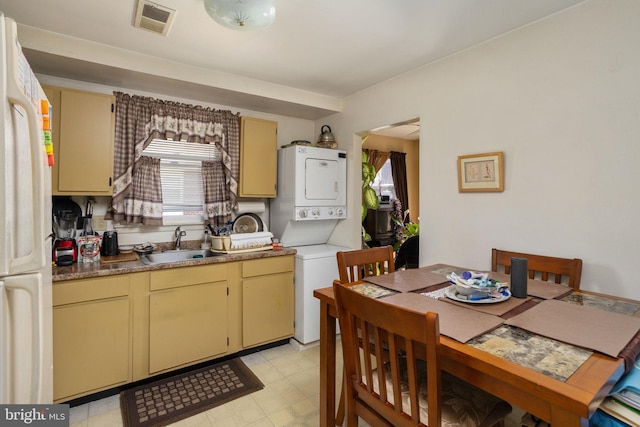 kitchen featuring sink, stacked washing maching and dryer, and white refrigerator