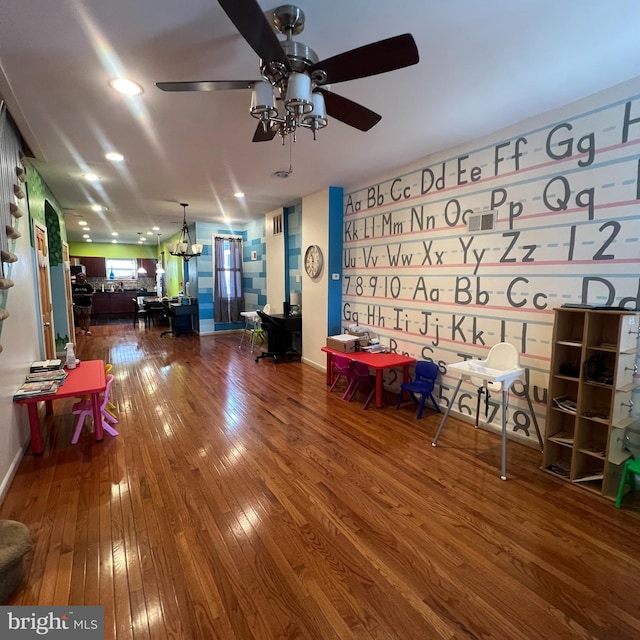 interior space featuring ceiling fan with notable chandelier and hardwood / wood-style flooring