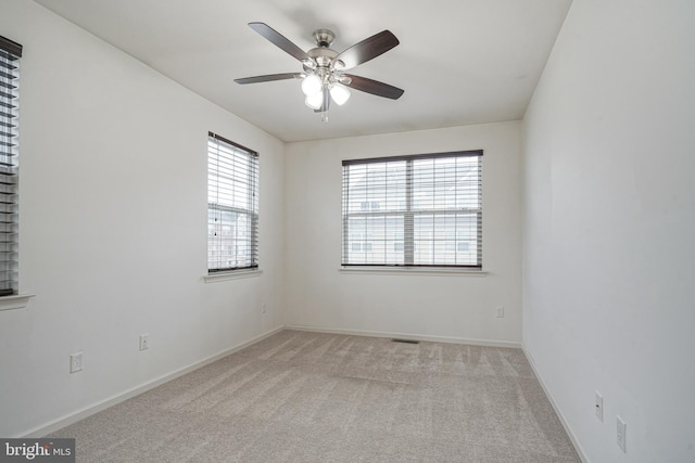 empty room with ceiling fan and light carpet