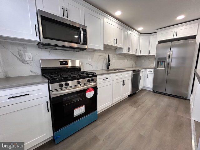 kitchen featuring white cabinetry, sink, stainless steel appliances, and light wood-type flooring