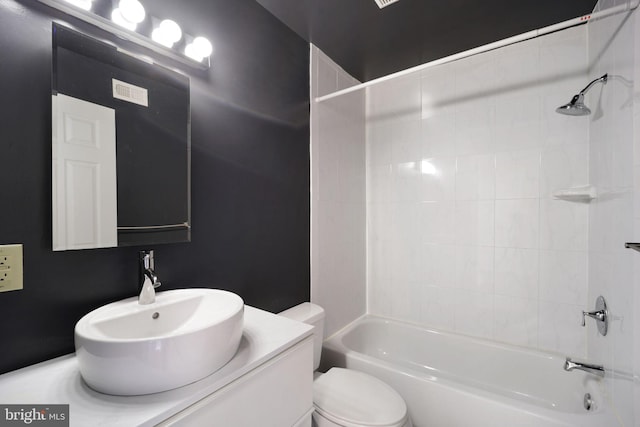 full bathroom featuring tiled shower / bath combo, toilet, and vanity