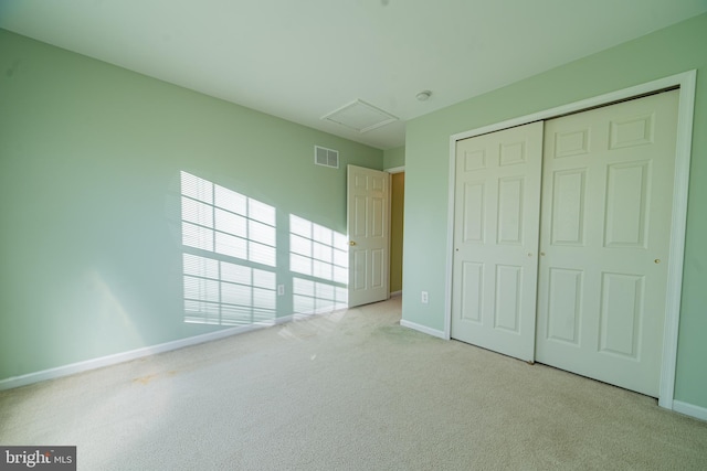 unfurnished bedroom featuring light carpet and a closet