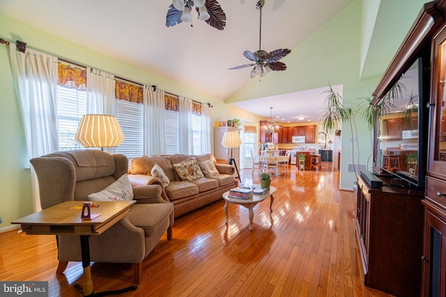 living room with high vaulted ceiling, light hardwood / wood-style floors, and ceiling fan with notable chandelier