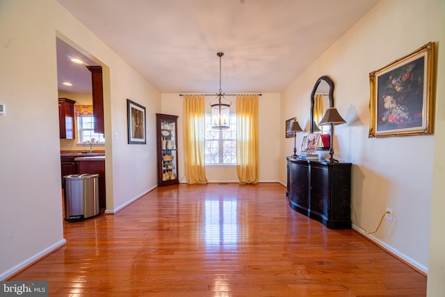 dining space featuring wood-type flooring, a wealth of natural light, a notable chandelier, and sink