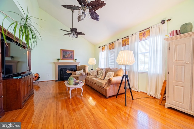 living room with ceiling fan, light wood-type flooring, and vaulted ceiling