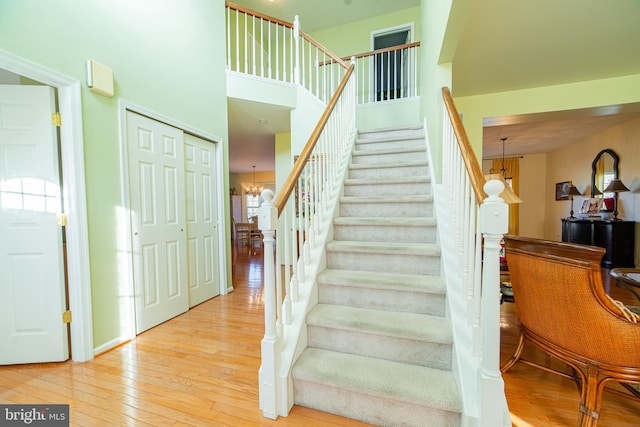 stairway featuring a chandelier, a towering ceiling, and wood-type flooring