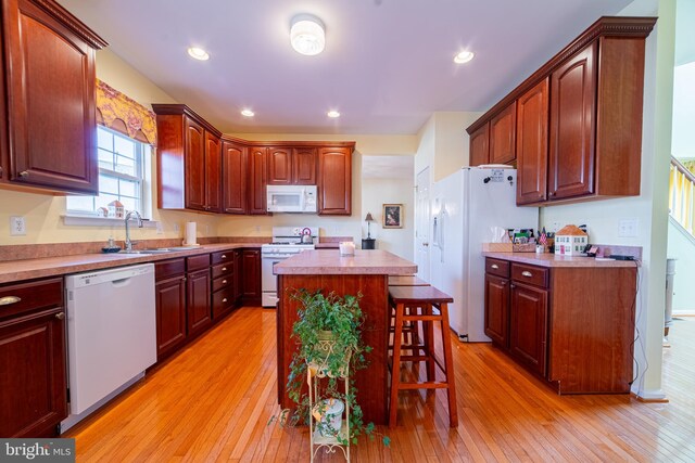 kitchen featuring a kitchen breakfast bar, a center island, white appliances, and light hardwood / wood-style flooring