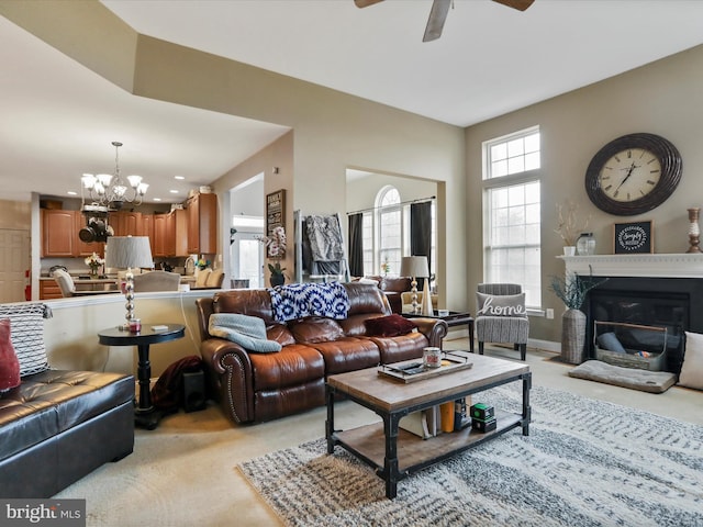 carpeted living room featuring ceiling fan with notable chandelier