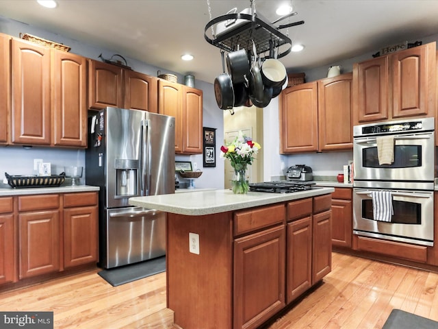 kitchen with a kitchen island, appliances with stainless steel finishes, and light hardwood / wood-style flooring