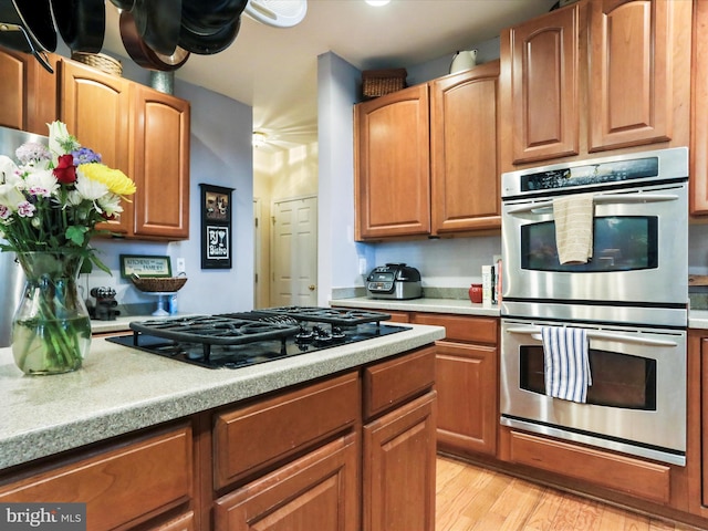 kitchen featuring black gas stovetop, light hardwood / wood-style floors, and stainless steel double oven