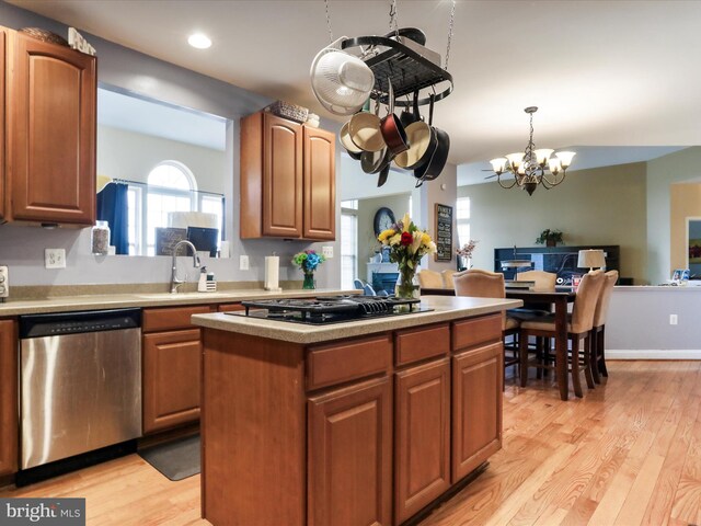 kitchen with sink, hanging light fixtures, stainless steel dishwasher, black gas stovetop, and light hardwood / wood-style flooring