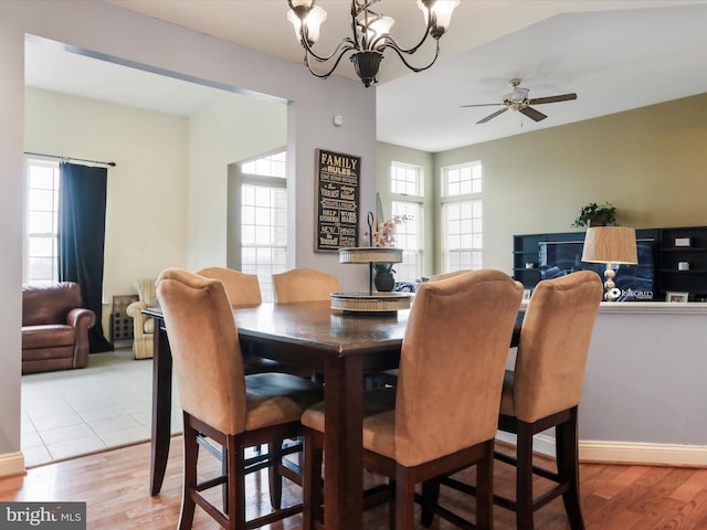 dining space featuring ceiling fan with notable chandelier and light hardwood / wood-style flooring